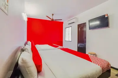 two beds in a room with a red wall at Super Hotel O By OYO Maruthi Gandhi Park in Coimbatore