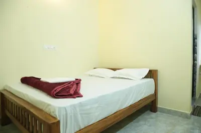a bed with two pillows and a red blanket on it at Thulir Homestay Valparai in Vālpārai