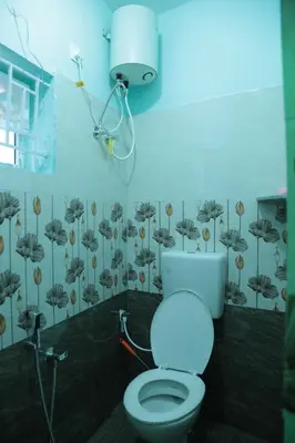 a bathroom with a white toilet and a shower at Thulir Homestay Valparai in Vālpārai