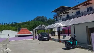 a motorcycle parked in a parking lot next to a building at Thulir Homestay Valparai in Vālpārai