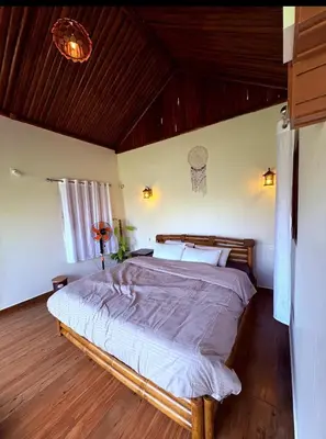 a bedroom with a large bed in a room at carpa lupa 1 waterfront bamboo cottage wayanad in Meenangadi