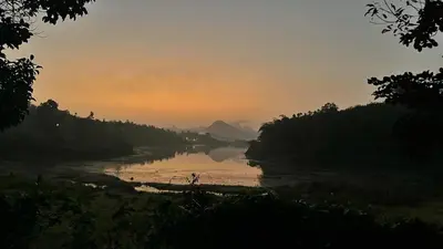 a view of a river at sunset at carpa lupa 1 waterfront bamboo cottage wayanad in Meenangadi