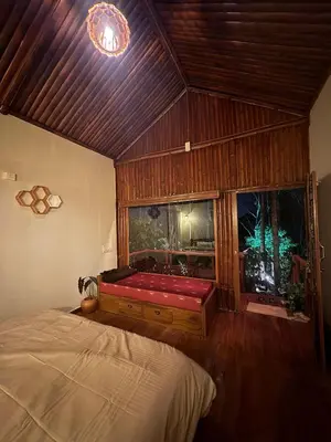 a bedroom with a red bed and a window at carpa lupa 1 waterfront bamboo cottage wayanad in Meenangadi