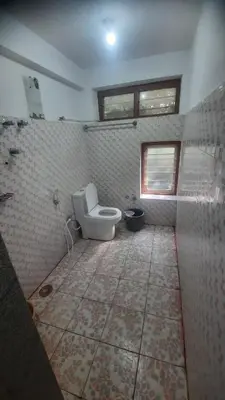a bathroom with a toilet and a tiled floor at Roshan Homestay in Madikeri