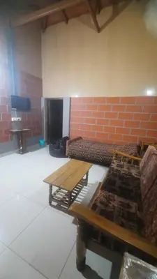 a room with two wooden tables and a brick wall at Roshan Homestay in Madikeri