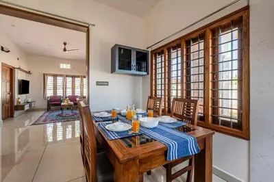 a dining room with a wooden table and chairs at White Meadows Mysore in Mysore