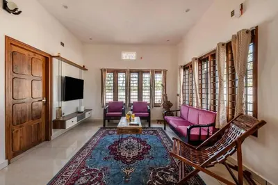 a living room with purple furniture and a tv at White Meadows Mysore in Mysore