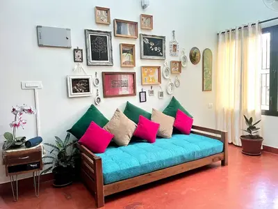 a living room with a blue couch with colorful pillows at House StoneHaven in Kaniyāmbetta