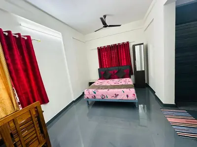 a bedroom with a bed and red curtains at Silver Gate Rooms in Kozhikode