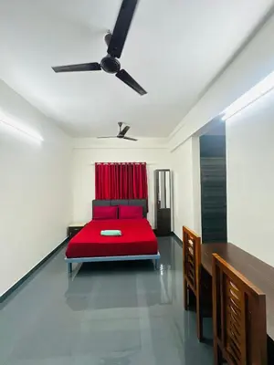 a red bed in a room with a ceiling fan at Silver Gate Rooms in Kozhikode