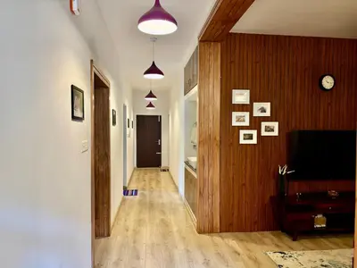 a hallway with a living room with a tv and wooden walls at Easters home in Kotagiri