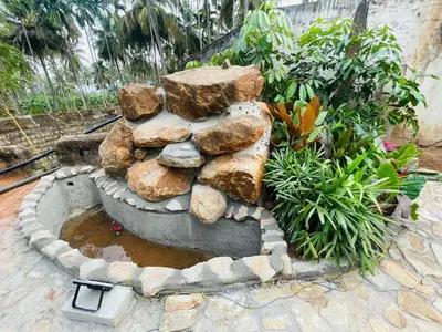 a stone fountain with rocks in a garden at Rajarajeshwari Farm Stay in Sivasamudram