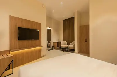 a hotel room with a bed and a flat screen tv at The Continental Suites in Kozhikode