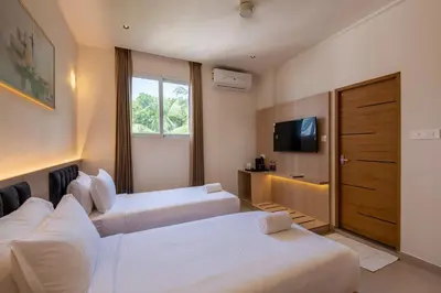 a hotel room with two beds and a television at The Continental Suites in Kozhikode