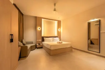 a bedroom with a bed and a couch and a mirror at The Continental Suites in Kozhikode