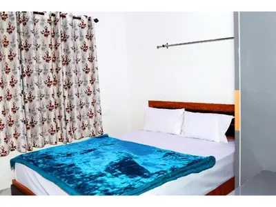 a bedroom with a bed with a blue blanket on it at Angels Nest 3BR FF near Karlad Lake by Homeyhuts in Padinjarathara