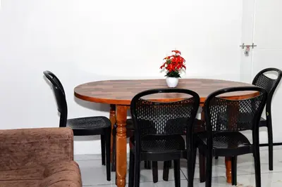 a wooden table with black chairs and a vase with flowers at Angels Nest 3BR FF near Karlad Lake by Homeyhuts in Padinjarathara