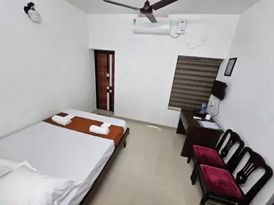 a bedroom with a bed and a table and chairs at Guruvayur Nest Homestay Duo in Guruvāyūr