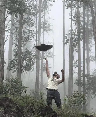 a man is holding up a kite in a forest at Canvo Vattavada in Vattavada