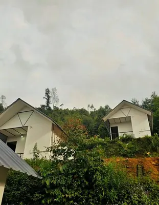 two white buildings sitting on top of a hill at Canvo Vattavada in Vattavada