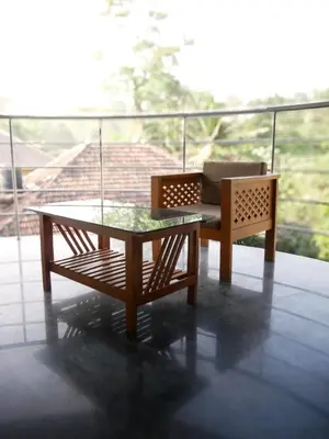 a coffee table and a chair on a balcony at Wayanad Pent House in Mananthavady