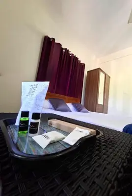 a hotel room with a table with a suitcase on a bed at Wayanad Pent House in Mananthavady