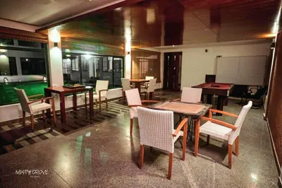 a dining room with tables and chairs and a pool at Misty Grove Resort, Gudalur in Devāla