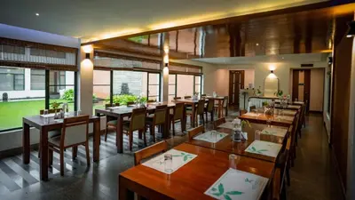 a restaurant with wooden tables and chairs and windows at Misty Grove Resort, Gudalur in Devāla