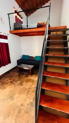 a living room with a staircase and a couch at Nyra homestay in Kushālnagar