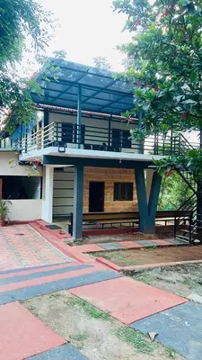 a building with a balcony and a bench in front of it at Nyra homestay in Kushālnagar