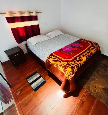 a small bedroom with a bed with a colorful blanket at Nyra homestay in Kushālnagar
