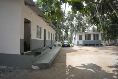 a car parked next to a building with palm trees at River view farm stay in Anaimalai