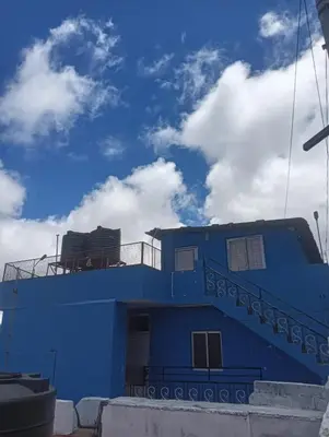 a blue building with the sky in the background at Yamuna cottage in Ooty