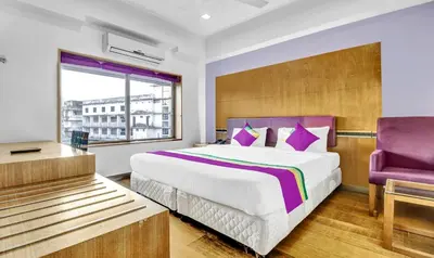 a bedroom with a large bed and a purple chair at Medora Hotel by Rak Rooms in Kozhikode