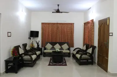 a living room with chairs and a couch and a tv at Grace Guest Home in Trichūr