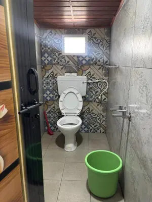 a bathroom with a toilet and a green bucket at The Retreat in Vālpārai