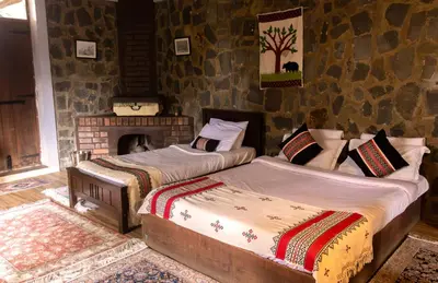 two beds in a room with a fireplace at Hullathy by Red Earth in Ooty