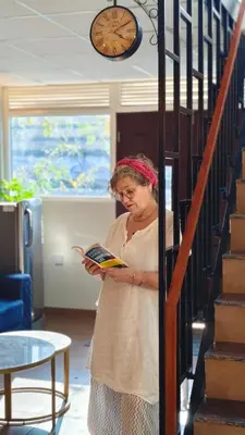 a woman standing in a room reading a book at Oblue Private Pool Villa in Cherai Beach