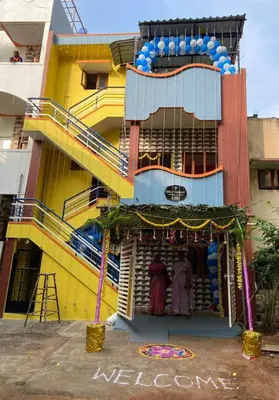 a yellow building with a store in front of it at Holy Family Nest 2 in Mysore
