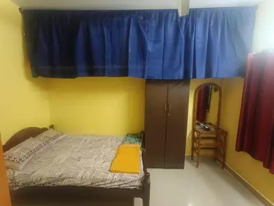 a bedroom with a bed and a blue curtain at Holy Family Nest 2 in Mysore