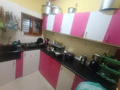 a kitchen with pink and white cabinets with pots and pans at Holy Family Nest 2 in Mysore