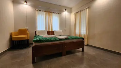 a bedroom with a bed and a yellow chair at The Bear's Lair 2BHK Chembra Peak View in Vythiri