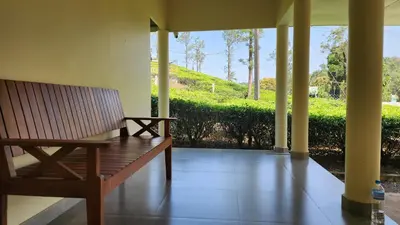 a wooden bench sitting on the porch of a house at The Bear's Lair 2BHK Chembra Peak View in Vythiri