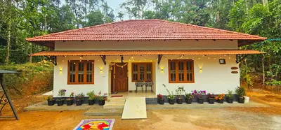 a small white house with a red roof at Mamoksha Riverdale in Padinjarathara