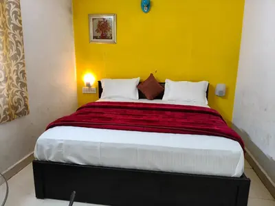 a bedroom with a large bed with a yellow wall at White House Cottage in Ooty