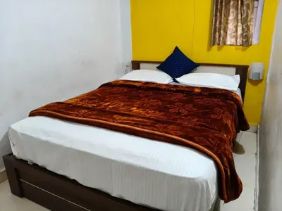 a bedroom with a large bed with a blanket on it at White House Cottage in Ooty