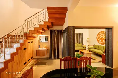 a living room with a staircase with a green couch at Antara Luxury Homestay in Alwaye