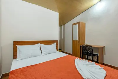 a bedroom with a bed with an orange blanket at Grape Rooms in Perintalmanna