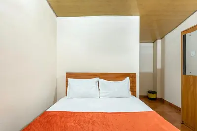 a bedroom with a bed with an orange blanket at Grape Rooms in Perintalmanna