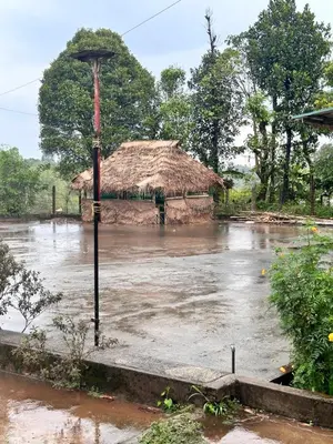 a flooded street with a thatched building and water at Coffee land in Kaniyāmbetta